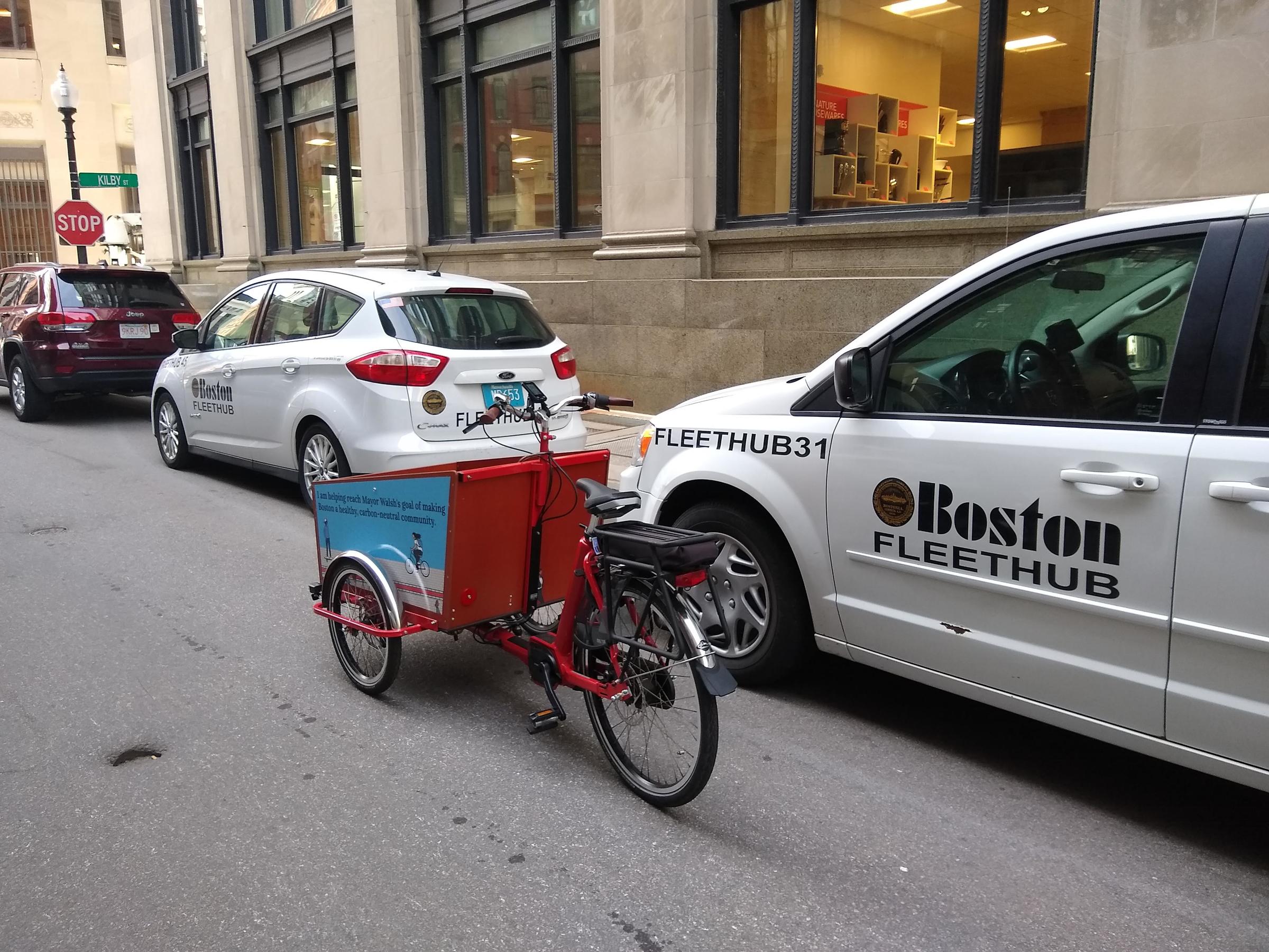 City of Boston cargo tricycle parked near City of Boston central fleet vehicles