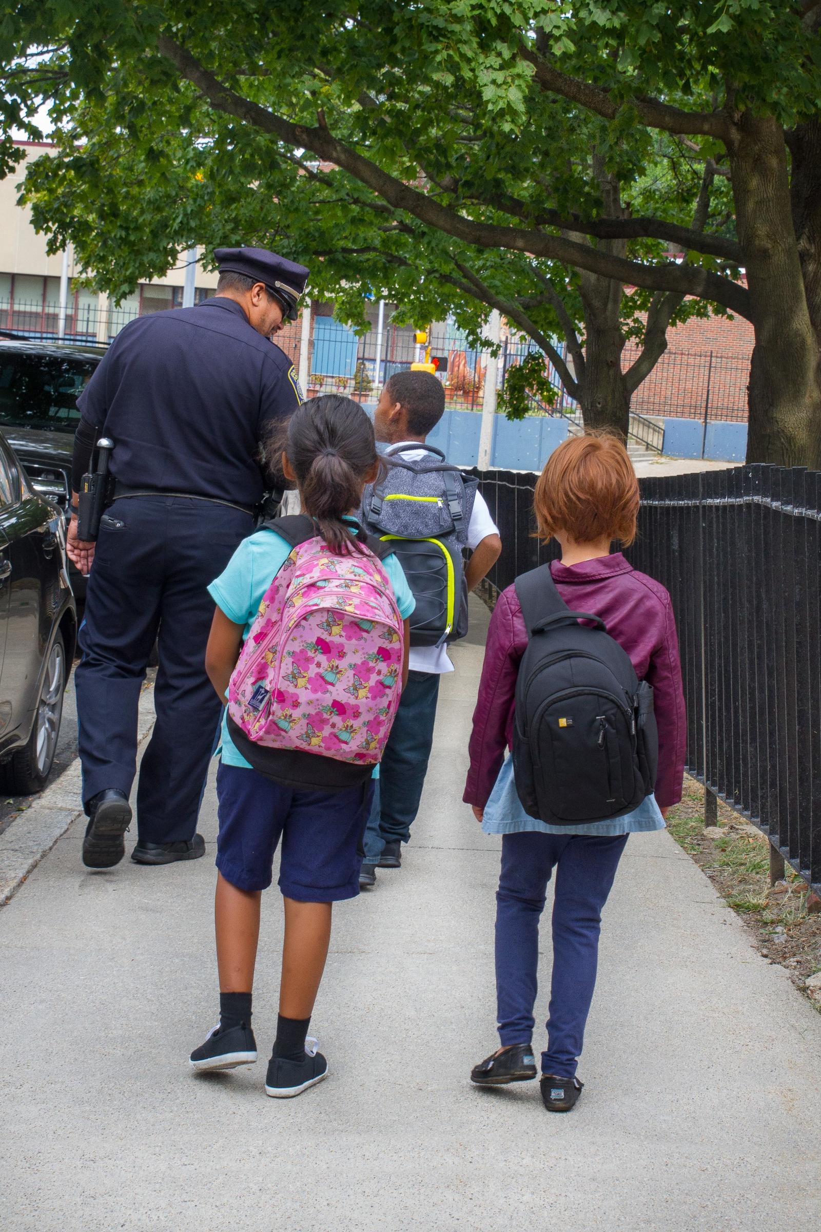 Children walking to school alongside a police officer