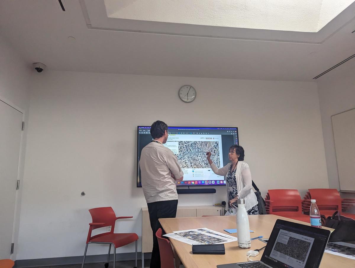 Image shows a BTD planner discussing Poplar Street with a constituent in front of a screen showing plans for speed humps, a contraflow bike lane, and potential other changes.