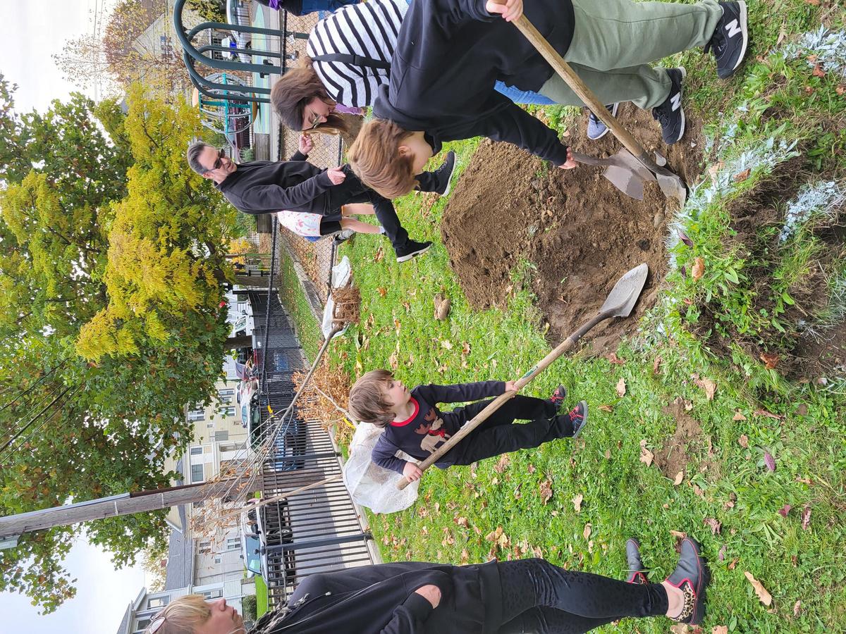 Three children dig a hole with spades in Hobart Park.