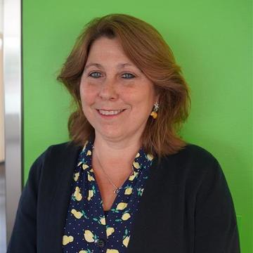 Mary Skipper's headshot, there is a green screen in the background.